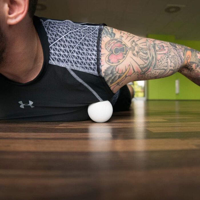 Mann benutzt Lacrosse Ball für Triggerpunkt Massage Weiss