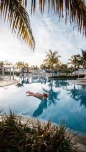 Eine Frau in weissem Badekleid springt kopfüber in einen Pool