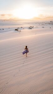 Eine Frau in violettem Kleid läuft durch die Wüste