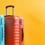 Vier bunte Koffer stehen auf einem gelben Hintergrund in einer Reihe. Die Koffer sind unterschiedlich in Farbe und Größe und scheinen gut gepflegt zu sein. Konzept von Organisation und Vorbereitung.