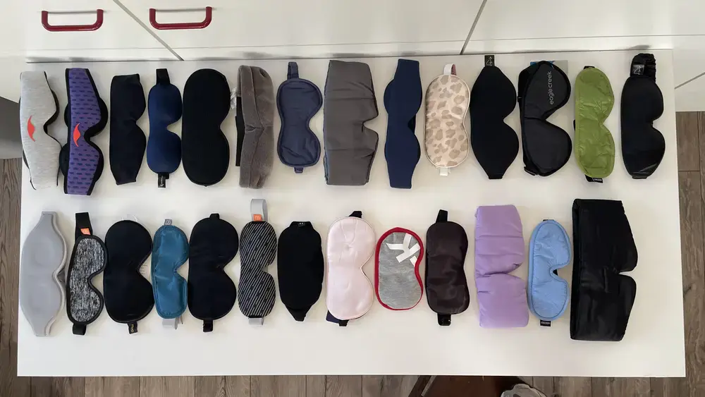 Übersicht aller Schlafmasken aus dem Sortiment von Lemali.ch – verschiedene Modelle in diversen Farben und Materialien nebeneinander auf weissem Tisch angeordnet