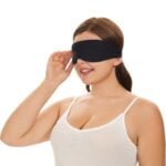 Frau mit schwarzer Schlafmaske, die die bequeme Passform und den lichtblockierenden Effekt zeigt.