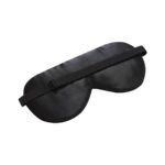 Schwarze Schlafmaske mit verstellbarem Band, auf eine glatte Oberfläche gelegt.