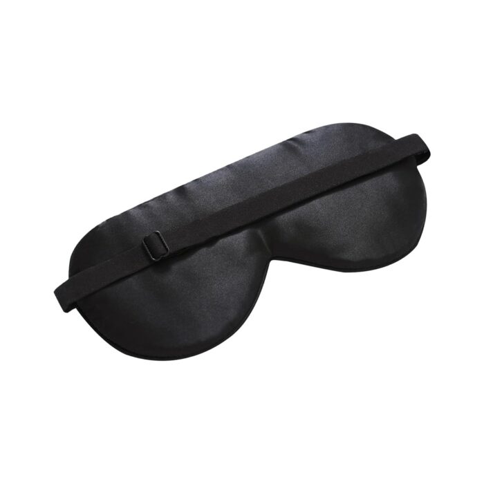 Schwarze Schlafmaske mit verstellbarem Band, auf eine glatte Oberfläche gelegt.