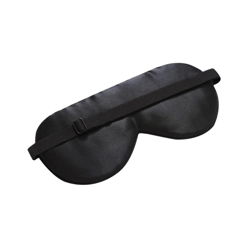 Schwarze Schlafmaske mit verstellbarem Band, auf eine glatte Oberfläche gelegt.