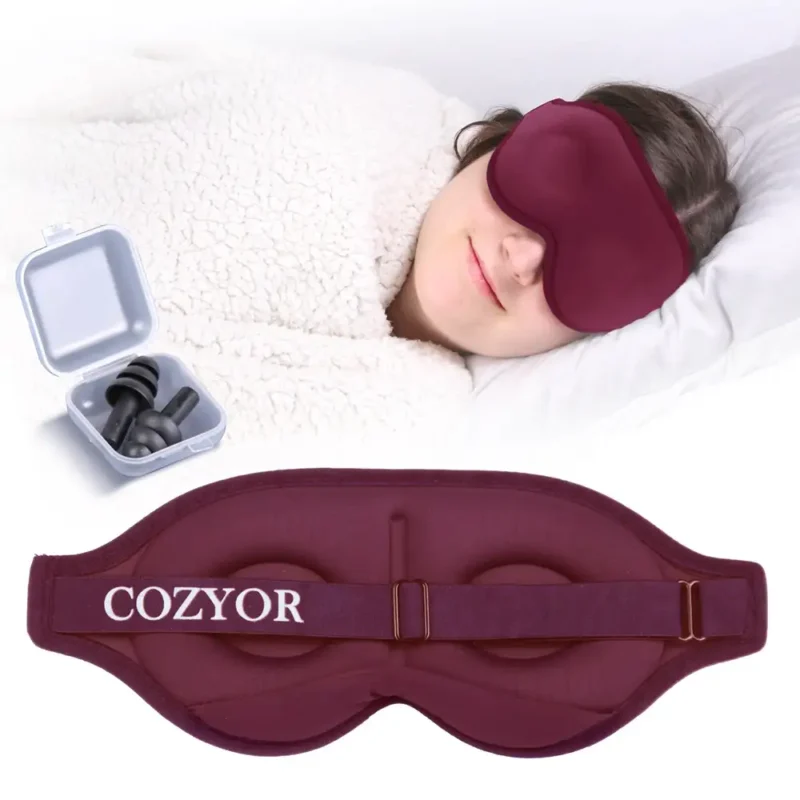 Schlafmaske und Ohrstöpsel für ungestörten Schlaf. Eine Person liegt entspannt im Bett mit einer dunkelroten ergonomischen Schlafmaske, während daneben eine Box mit Ohrstöpseln geöffnet ist. Unten ist die verstellbare Rückseite der Schlafmaske zu sehen.