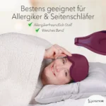 Schlafmaske und Ohrstöpsel für Allergiker und Seitenschläfer. Eine Person liegt auf der Seite, kuschelt sich in eine Decke und hebt leicht ihre dunkelrote Schlafmaske an. Oben rechts eine Nahaufnahme des 15° angewinkelten Designs.