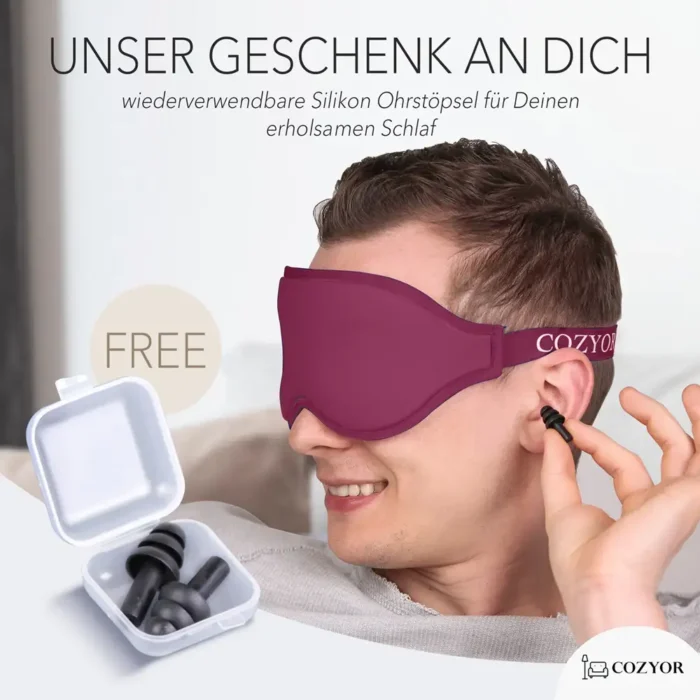Schlafmaske und Ohrstöpsel im Set. Ein Mann trägt eine dunkelrote Schlafmaske und setzt sich ein Paar wiederverwendbare Silikon-Ohrstöpsel ein, während eine geöffnete Aufbewahrungsbox mit weiteren Ohrstöpseln zu sehen ist.