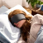 Eine Frau liegt seitlich auf einem weichen Kissen und schläft entspannt mit einer gewichteten Schlafmaske. Die Schlafmaske passt sich sanft an ihr Gesicht an und sorgt für eine dunkle, beruhigende Schlafumgebung.