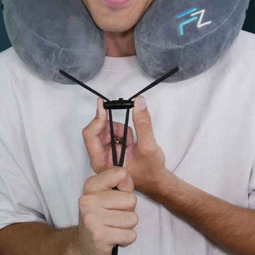 Nahaufnahme eines Reise-Nackenkissens von Flowzoom mit verstellbarem Verschluss-System. Eine Person zieht an den elastischen Bändern, um das Kissen individuell anzupassen.