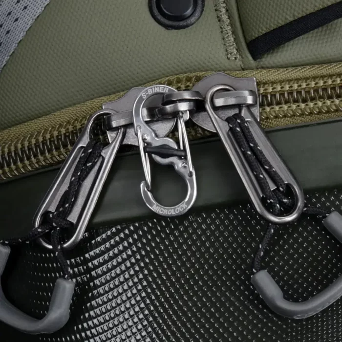 Zwei Reissverschlüsse eines Rucksacks sind mit einem silbernen Karabiner Schlüsselanhänger im S-Biner-Design gesichert, der an beiden Zippern befestigt ist.