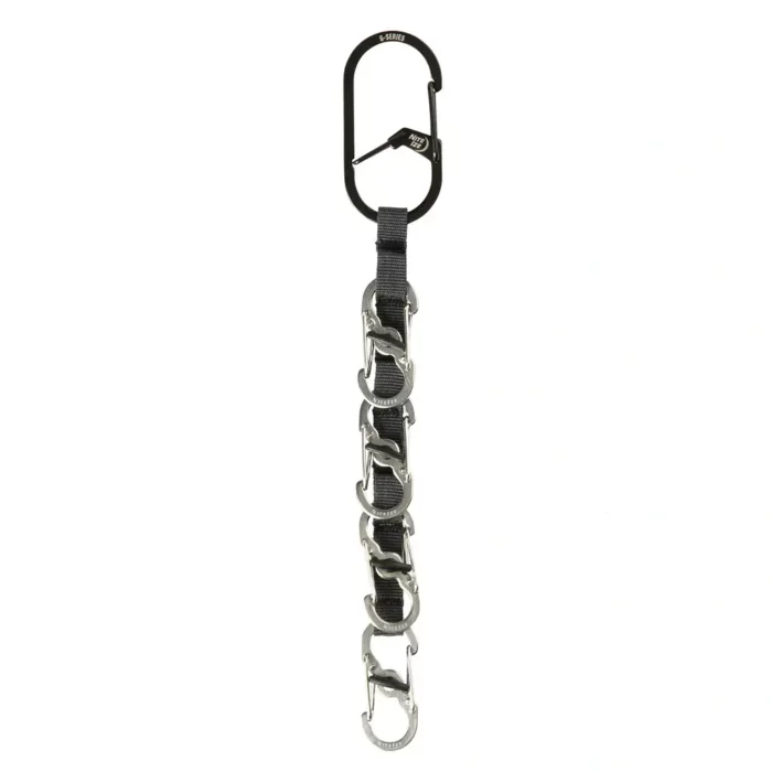 Schlüssel Karabiner mit schwarzem Hauptkarabiner und fünf kleinen silbernen Karabinern an einem schwarzen Gurtband vor weissem Hintergrund.
