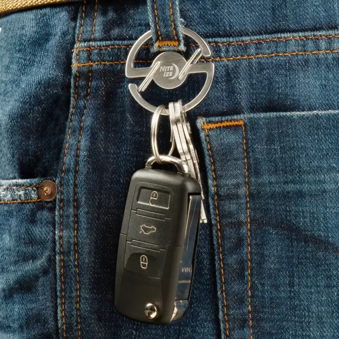 Schlüsselanhänger für Hosenbund mit speziellem Ringmechanismus ist an einer Gürtelschlaufe einer Jeans befestigt und hält mehrere Schlüssel sowie einen Autoschlüssel.