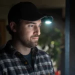 Ein Mann trägt eine Clip Lampe, die an der Krempe seiner Baseballkappe befestigt ist und nach vorne leuchtet.