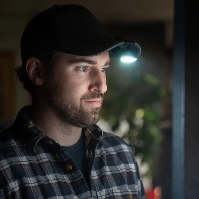 Ein Mann trägt eine Clip Lampe, die an der Krempe seiner Baseballkappe befestigt ist und nach vorne leuchtet.