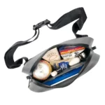 Die wasserdichte Gürteltasche ist geöffnet und zeigt ihren Inhalt – darunter Sonnencreme, Snacks, Getränkedose und weitere Utensilien für unterwegs.