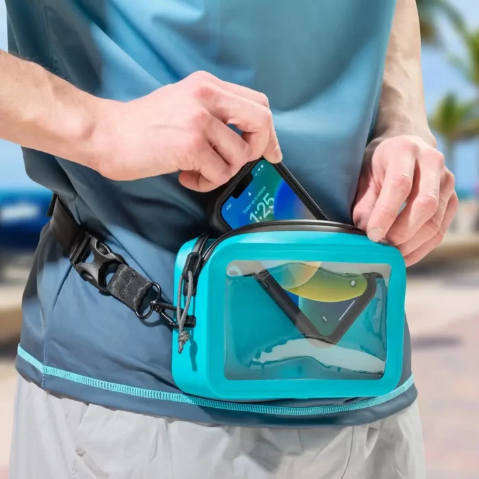 Person verstaut ein Smartphone in einer türkisfarbenen, wasserdichten Bauchtasche mit transparenter Fronttasche.