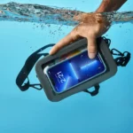 Hand greift unter Wasser nach einer grauen, wasserdichten Bauchtasche mit Smartphone hinter durchsichtigem Sichtfenster.