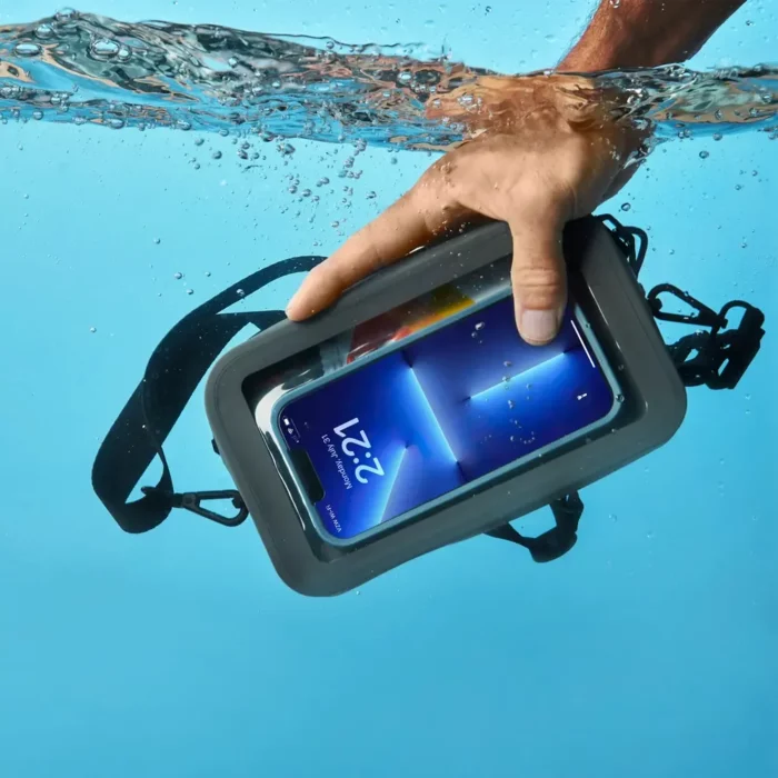 Hand greift unter Wasser nach einer grauen, wasserdichten Bauchtasche mit Smartphone hinter durchsichtigem Sichtfenster.