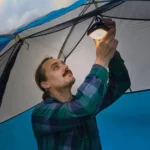 Mann befestigt eine Solar Campinglampe im Inneren seines Zelts.