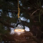 Solar Campinglampe mit warmem Licht hängt stimmungsvoll an einem Ast.