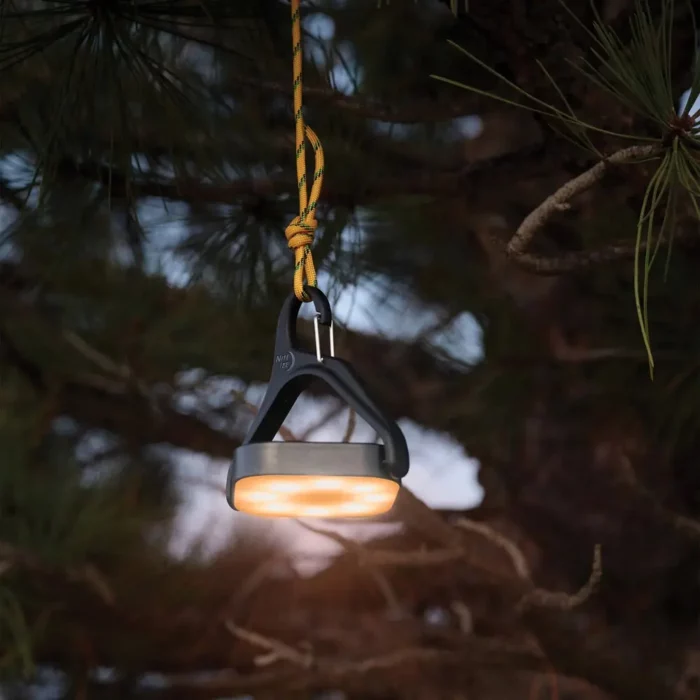 Solar Campinglampe mit warmem Licht hängt stimmungsvoll an einem Ast.