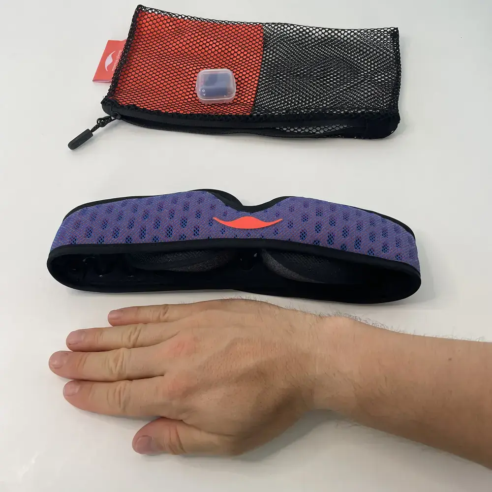 Größenvergleich der Manta Pro Schlafmaske mit einer ausgestreckten Hand daneben.