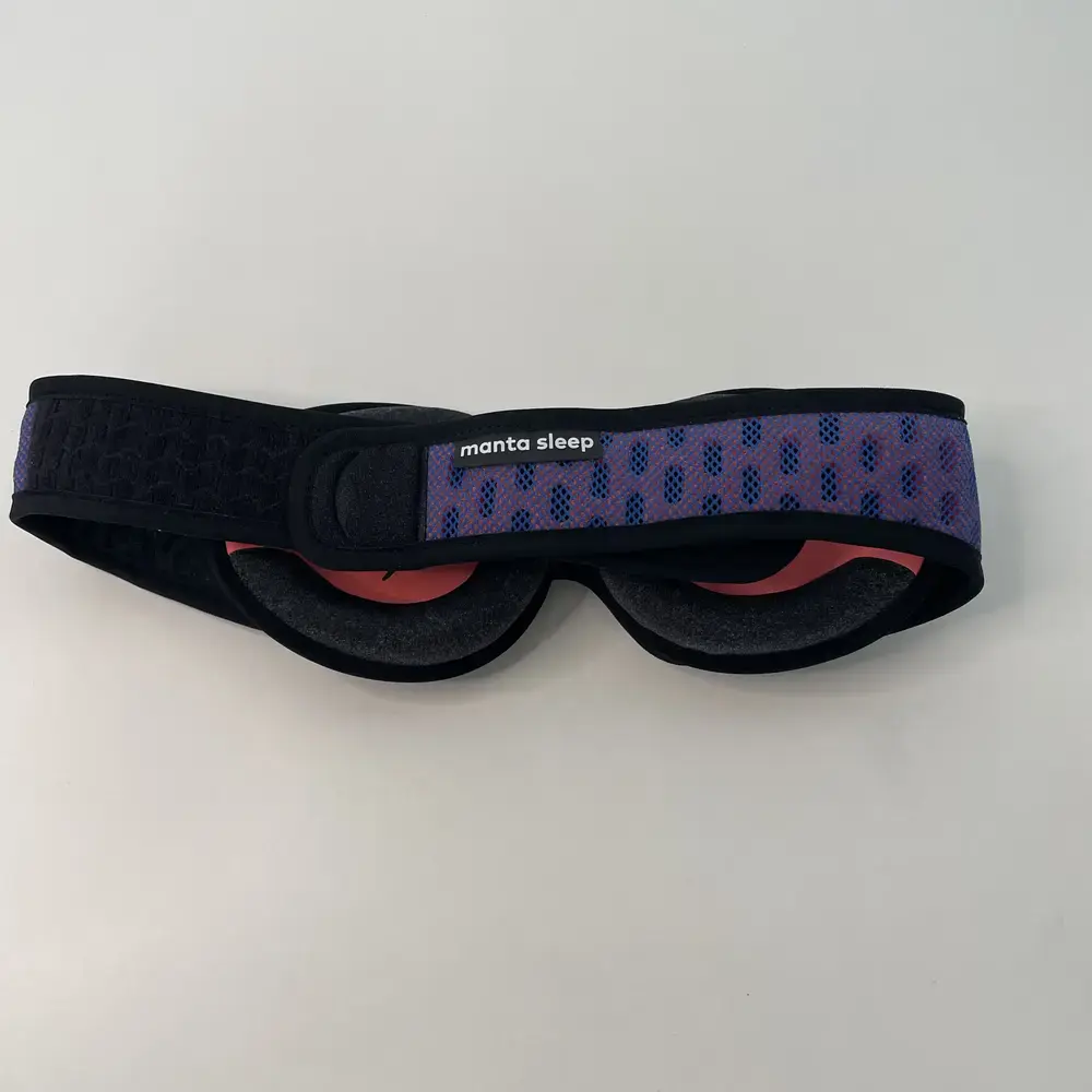 Rückansicht der zusammengerollten Manta Sleep Mask Pro mit sichtbarem Markenlabel.