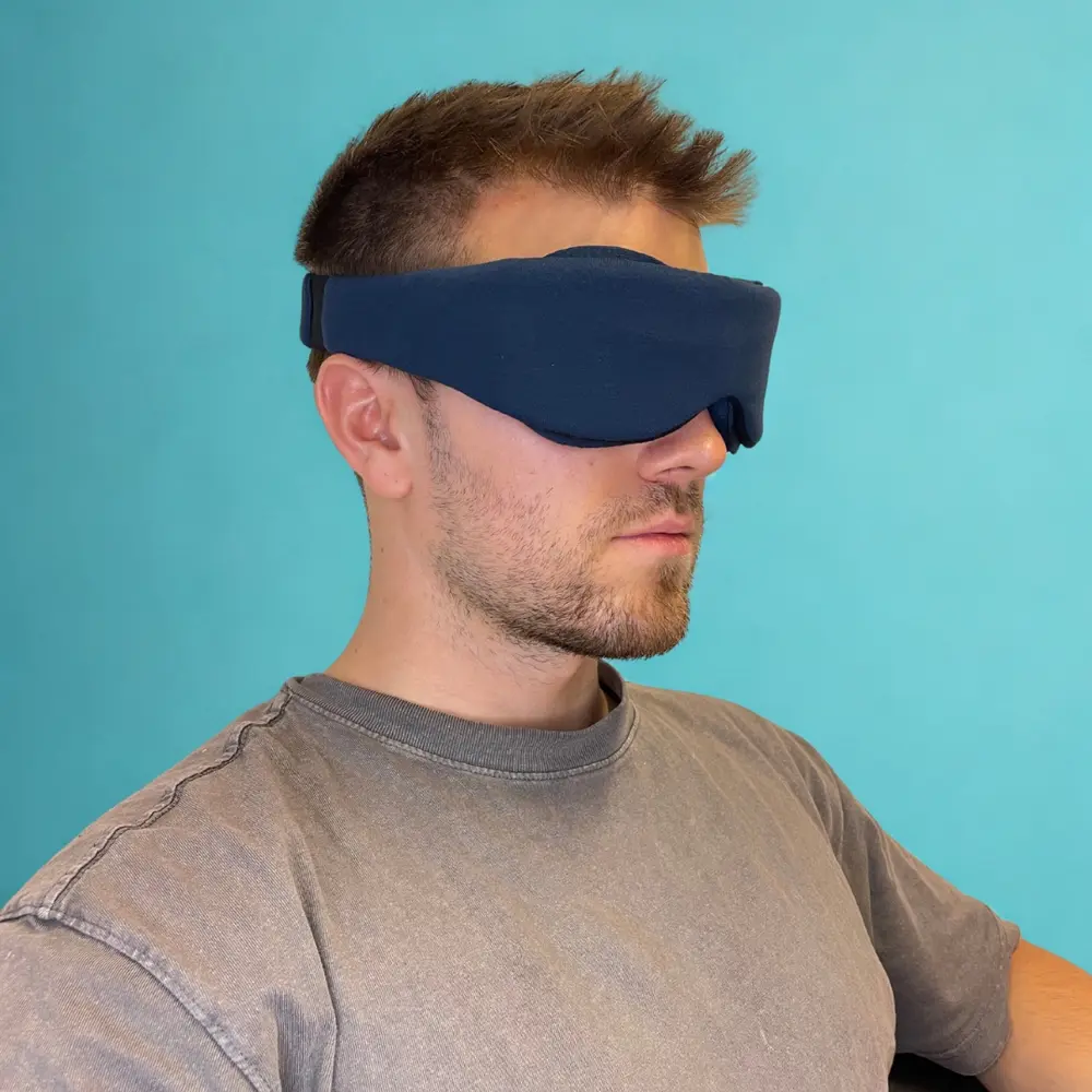 Ein Mann trägt die Schlafmaske, idealer Sitz für völlige Dunkelheit beim Schlafen.