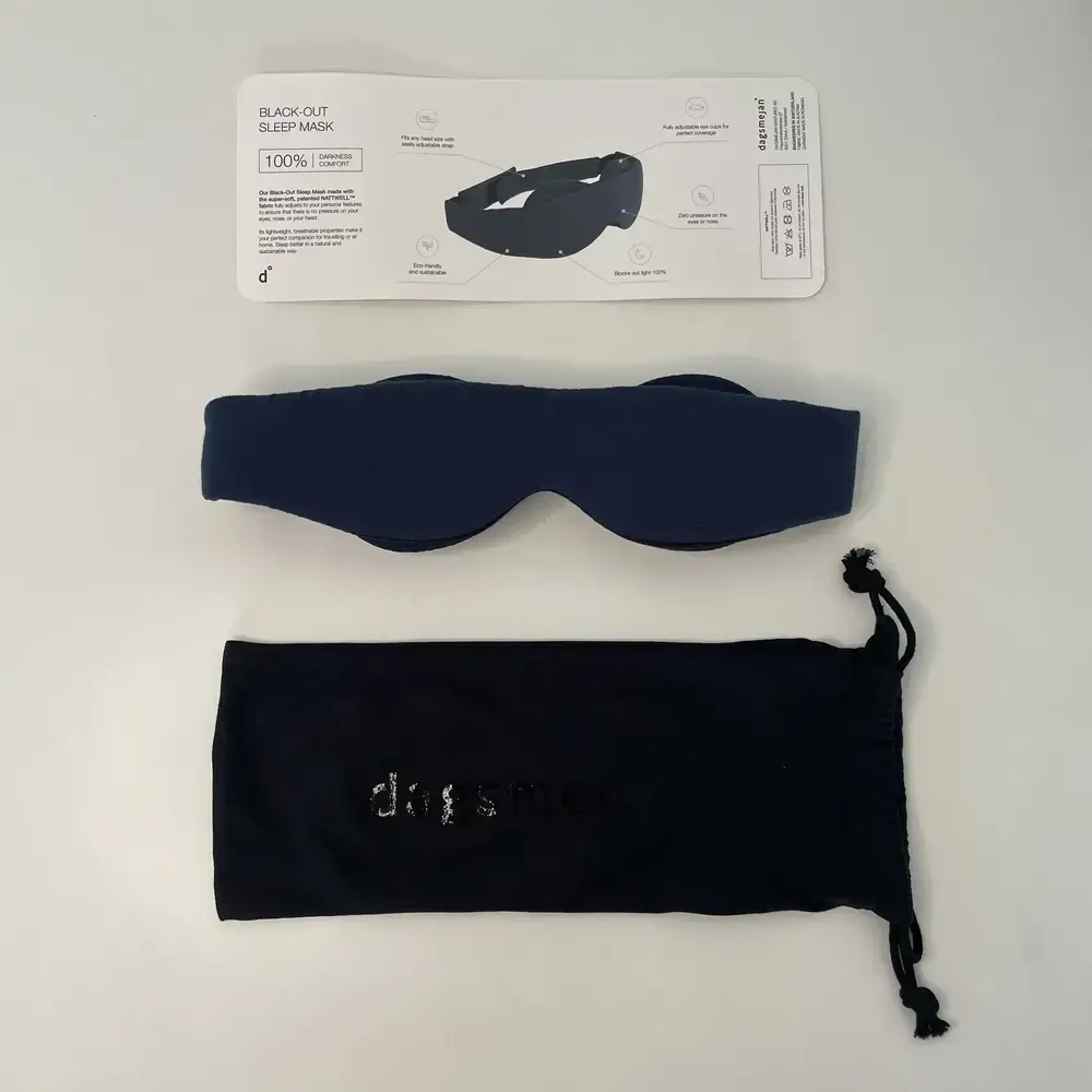 Schlafmaske mit Aufbewahrungsbeutel und Anleitung auf einem weißen Tisch arrangiert.