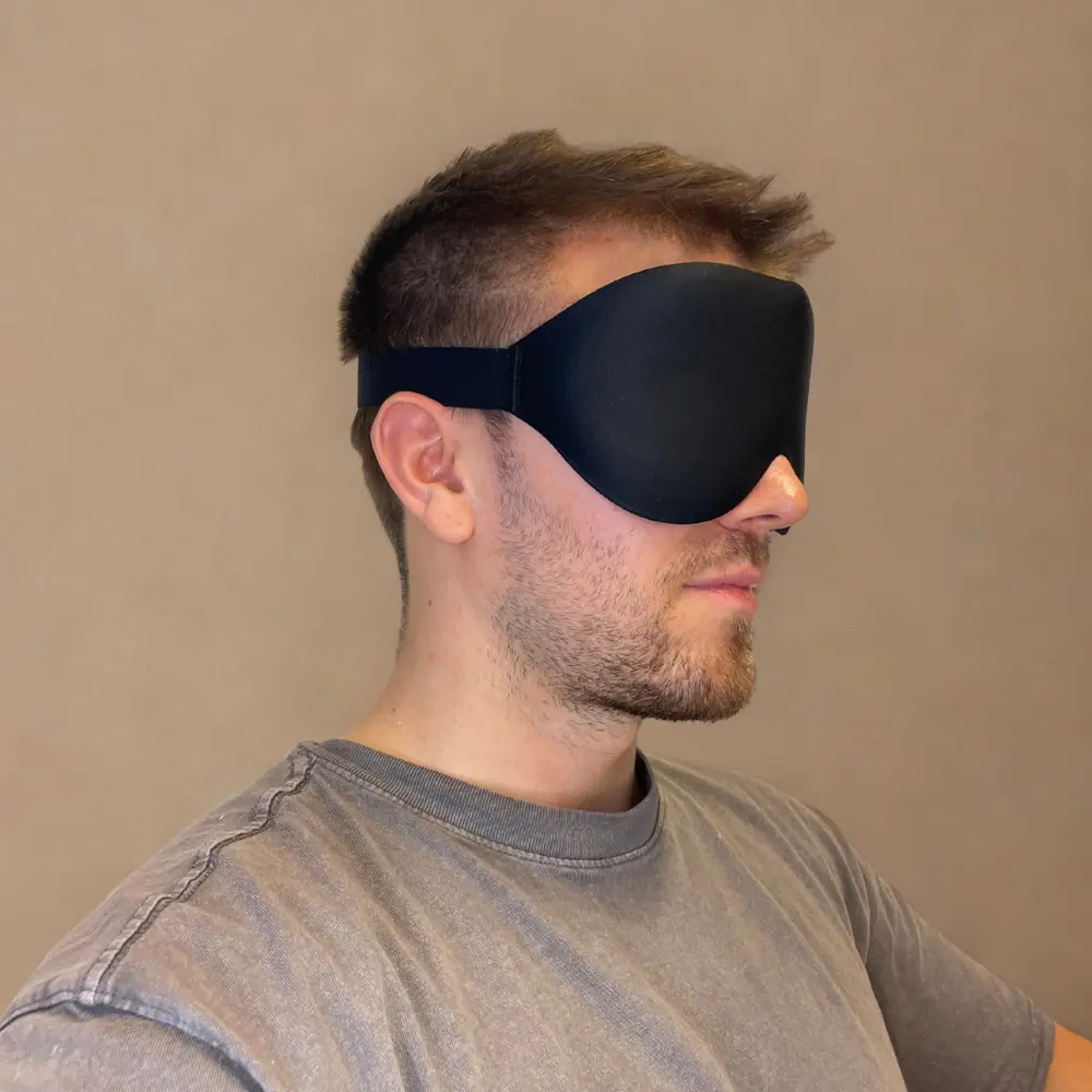 Mann trägt die ALASKA BEAR 3D Schlafmaske aus schwarzer Seide – komfortabler Sitz und vollständige Dunkelheit.
