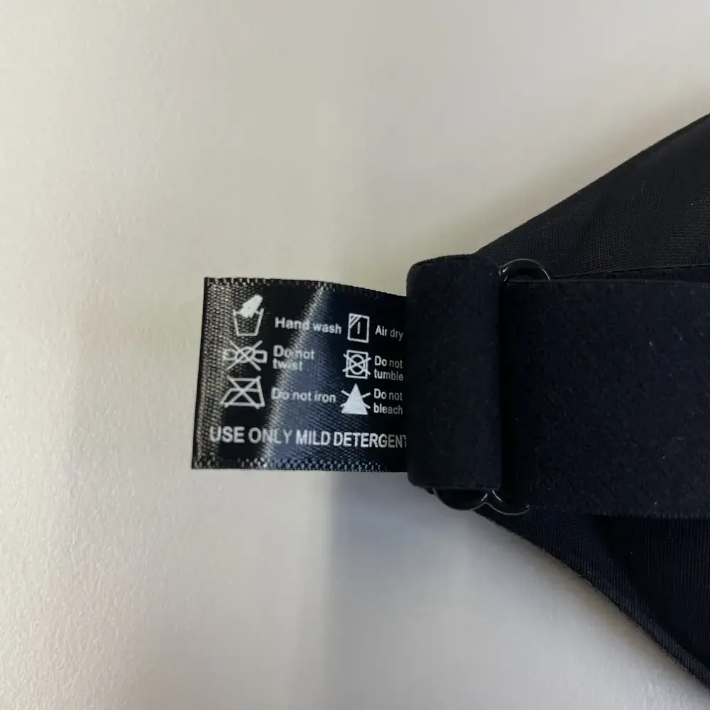 Nahaufnahme des Pflegeetiketts der ALASKA BEAR 3D Schlafmaske mit Wasch- und Pflegehinweisen.