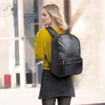 Frau mit schwarzem Go Travel Reiserucksack von hinten, unterwegs in urbaner Umgebung.