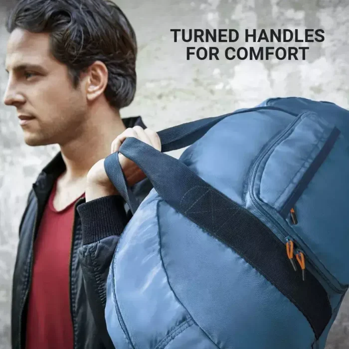 Mann trägt eine blaue faltbare Reisetasche von Go Travel mit gedrehten Griffen über der Schulter.