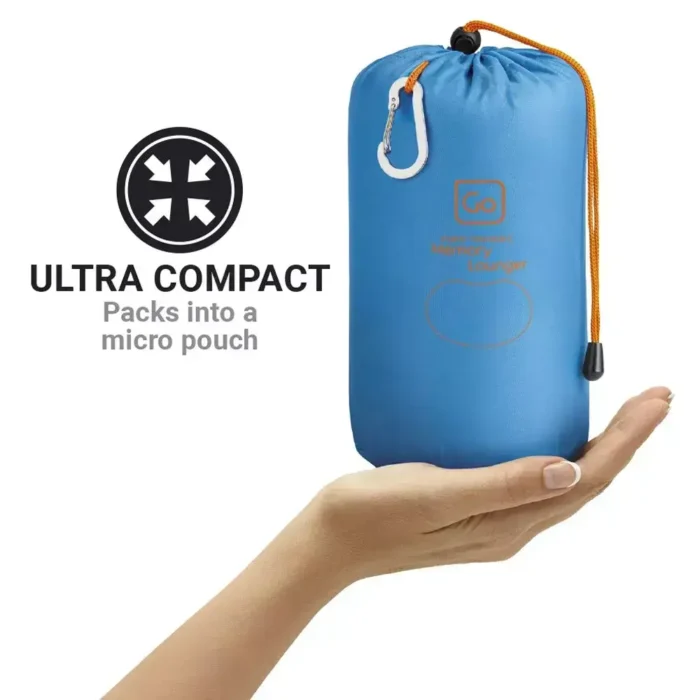 Zusammengepacktes Strandkissen der Marke Go Travel in blauer Transporttasche mit Karabiner, gehalten auf einer Hand.
