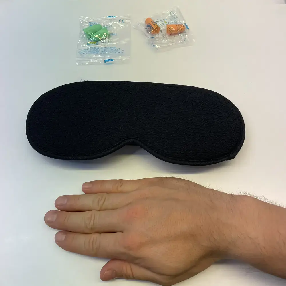 Gritin Schlafmaske mit Hand zum Grössenvergleich, inklusive zwei verpackter Ohrstöpsel