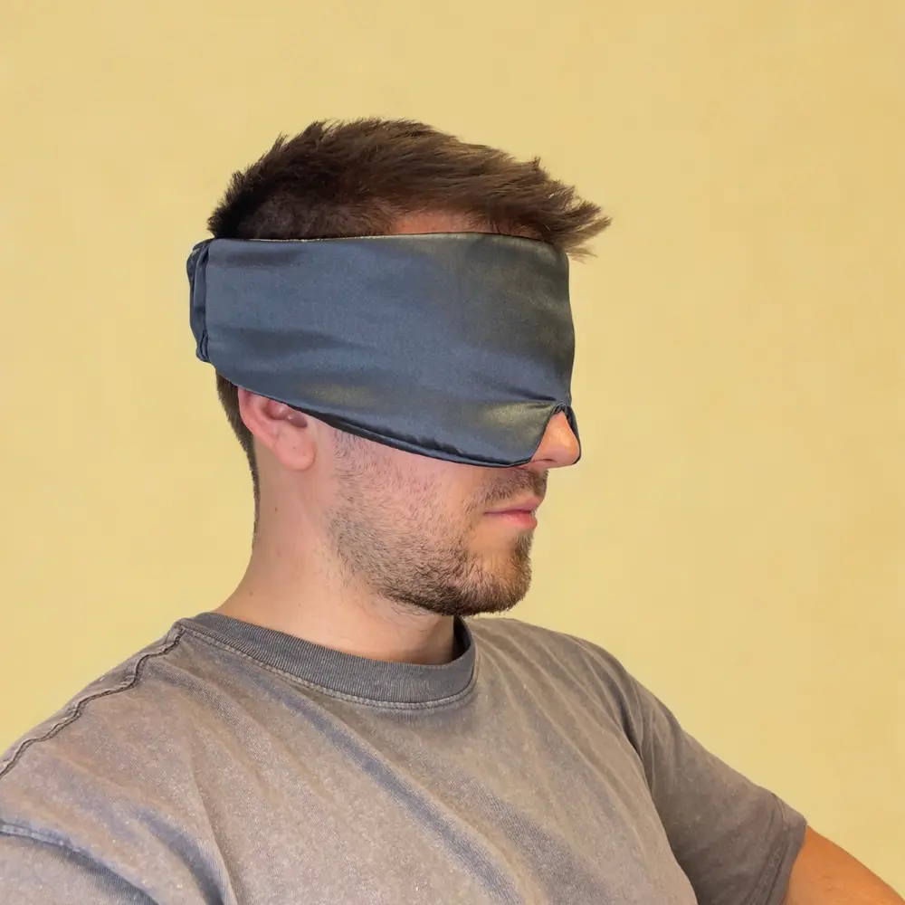 Seitenansicht der getragenen Kitsch Schlafmaske aus Satin an einem Mann vor gelbem Hintergrund
