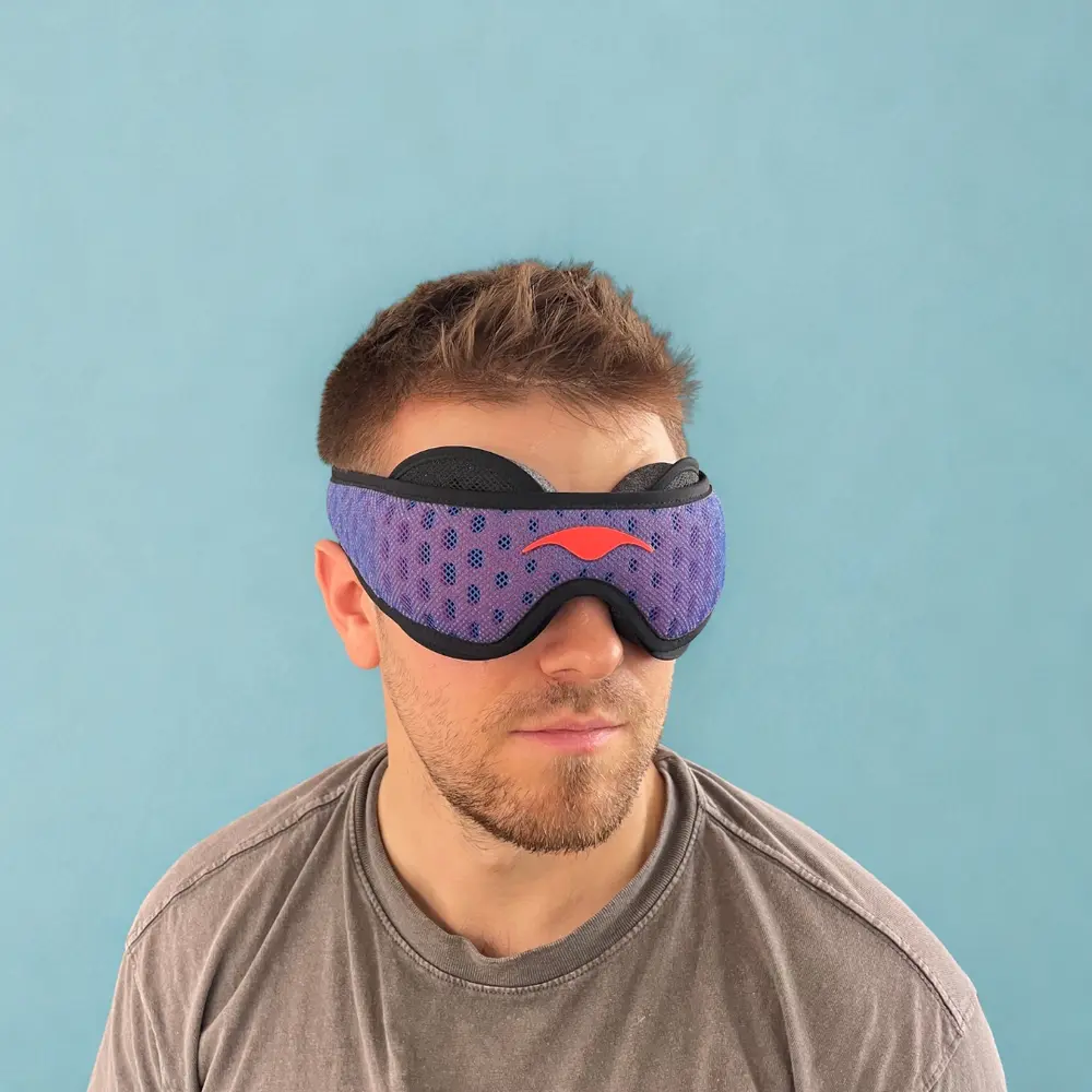 Mann mit aufgesetzter Manta Sleep Mask Pro von vorne – die gewölbten Augenmuscheln und das ergonomische Design sind deutlich sichtbar.