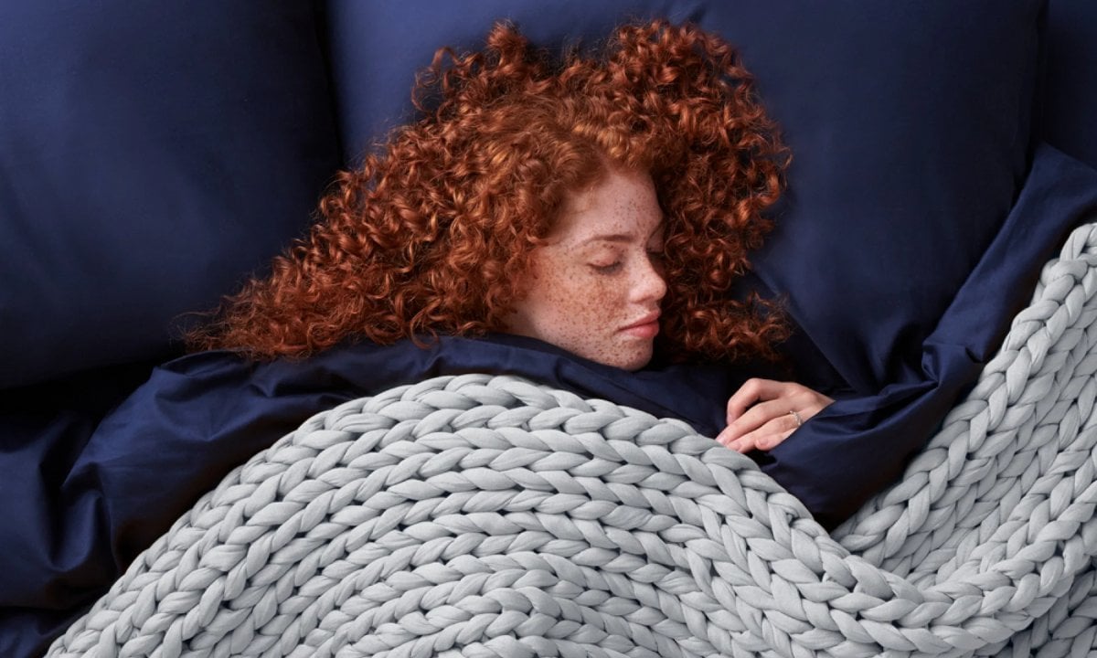 Frau schläft tief unter einer Bearaby Gewichtsdecke